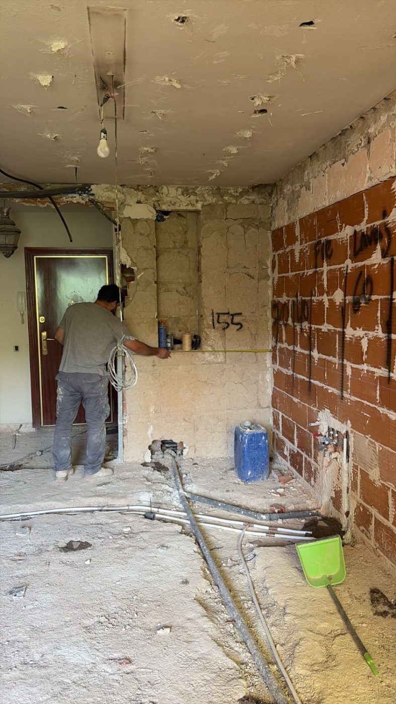 Operario tomando medidas sobre el muro de ladrillo tras la demolición