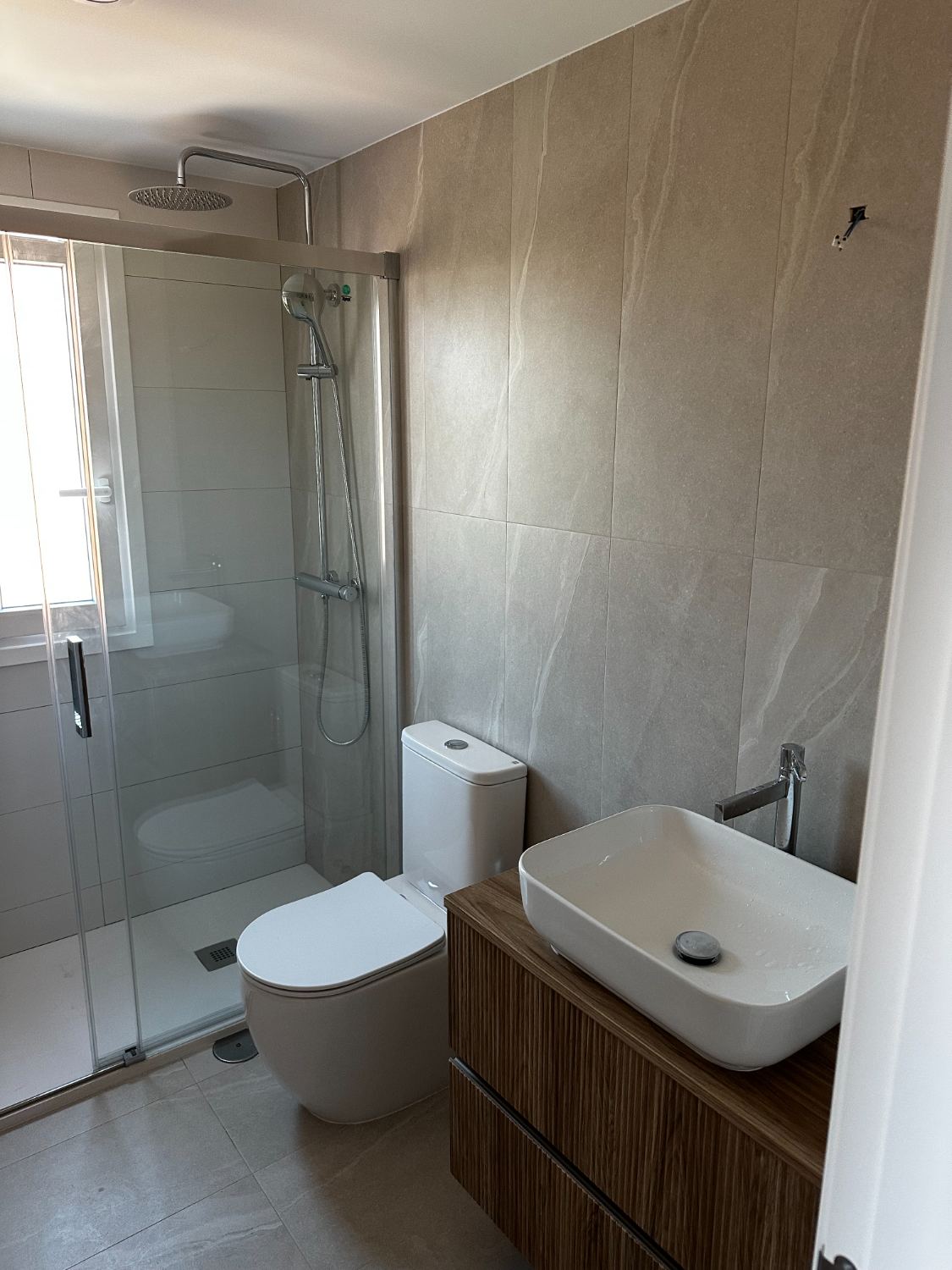 Baño terminado con plato de ducha, mueble suspendido y gres de gran formato