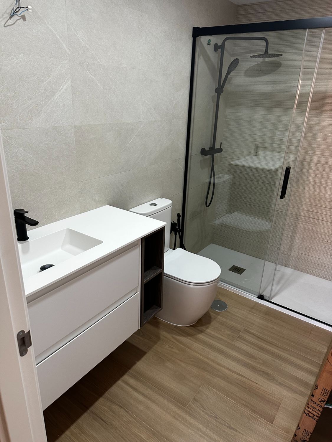 Baño terminado con mampara negra y mueble blanco a medida