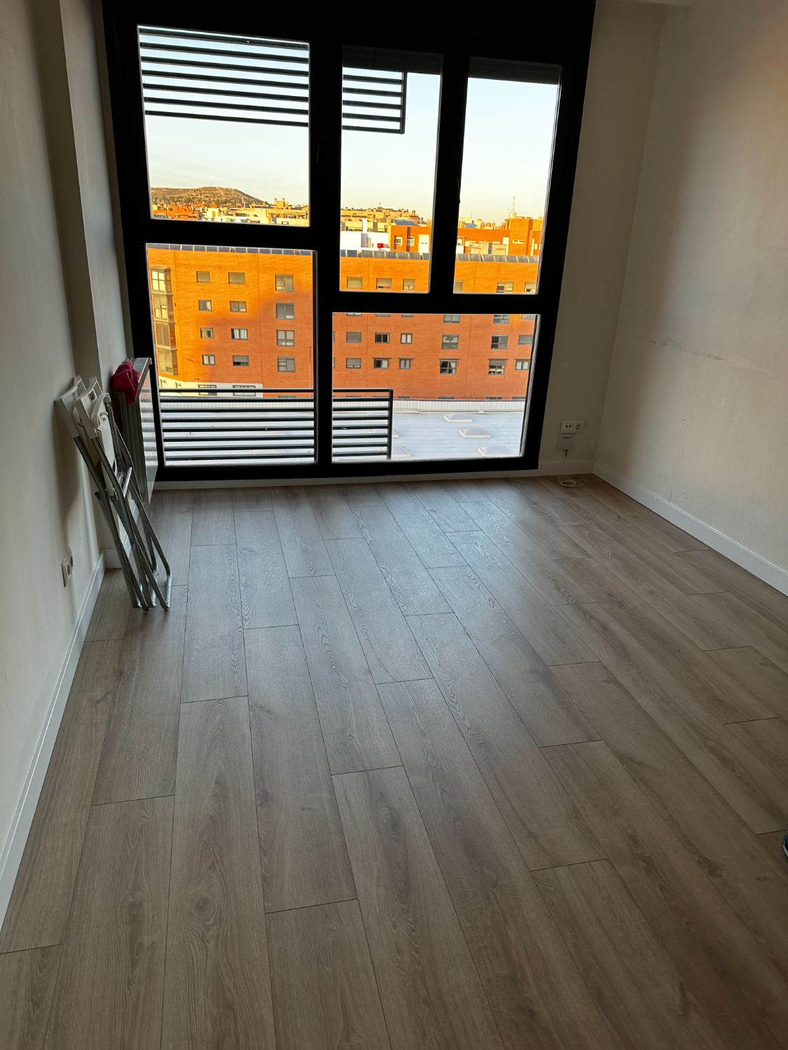 Dormitorio terminado con suelo laminado y ventanal al exterior
